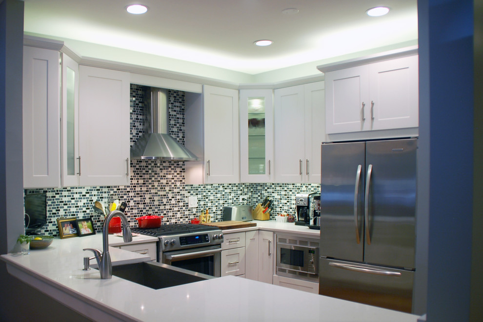 Inspiration for a mid-sized transitional kitchen remodel in Chicago with a farmhouse sink, shaker cabinets, white cabinets, quartz countertops, matchstick tile backsplash, stainless steel appliances, a peninsula and multicolored backsplash