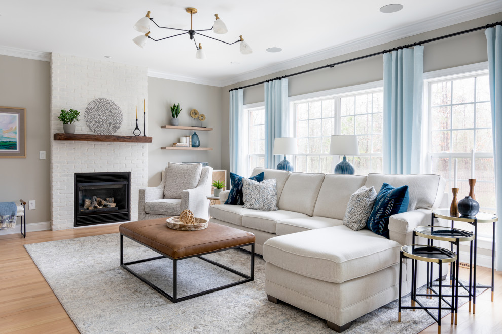 Photo of a mid-sized transitional open concept family room in Other with grey walls, light hardwood floors, a standard fireplace, a brick fireplace surround, a wall-mounted tv and brown floor.
