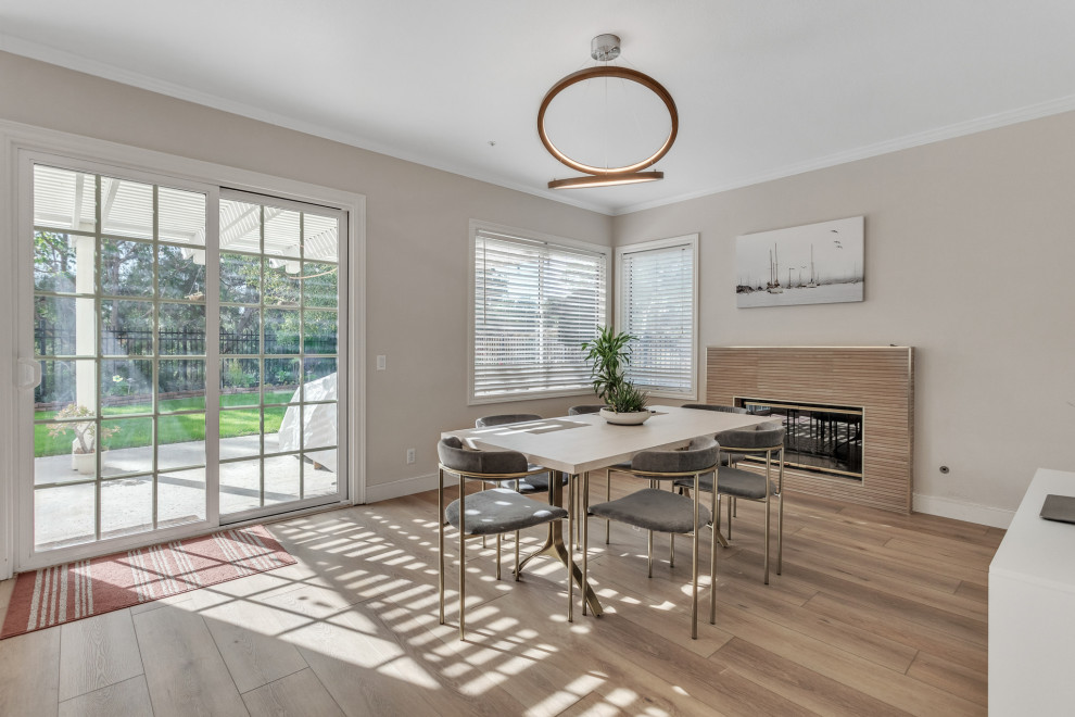 This is an example of a mid-sized modern kitchen/dining combo in Los Angeles with white walls, vinyl floors, a wood stove, a wood fireplace surround, beige floor and recessed.