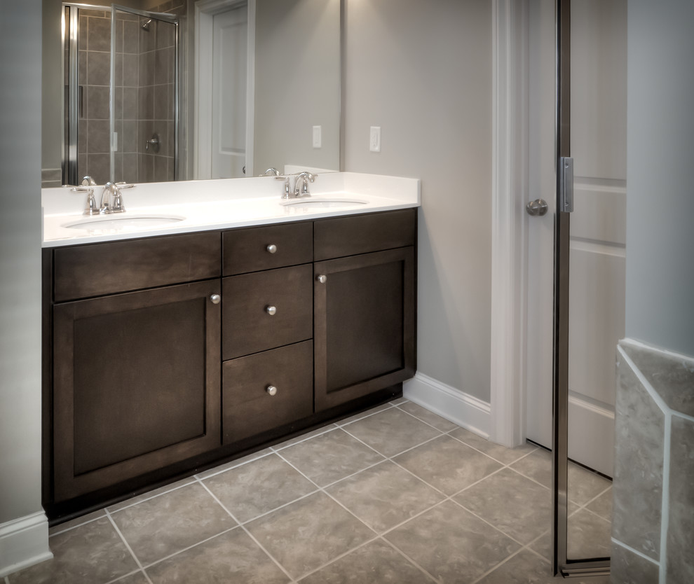 Mid-sized transitional bathroom in Atlanta with an undermount sink, shaker cabinets, dark wood cabinets, solid surface benchtops, a drop-in tub, an alcove shower, a one-piece toilet, gray tile, ceramic tile, grey walls and ceramic floors.