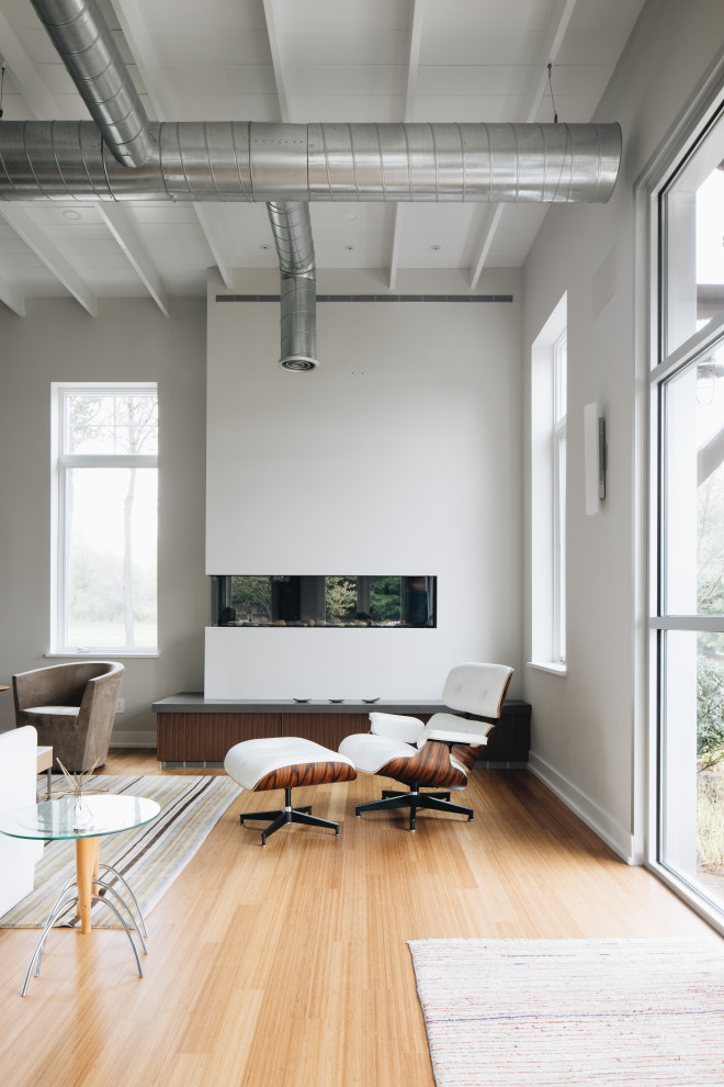 Esempio di un grande soggiorno minimal aperto con pareti grigie, parquet chiaro, camino ad angolo, nessuna TV e soffitto in legno