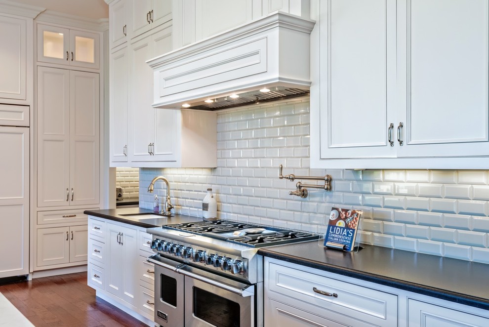 Large transitional single-wall dark wood floor open concept kitchen photo in Phoenix with a farmhouse sink, recessed-panel cabinets, white cabinets, white backsplash, subway tile backsplash, stainless steel appliances and an island