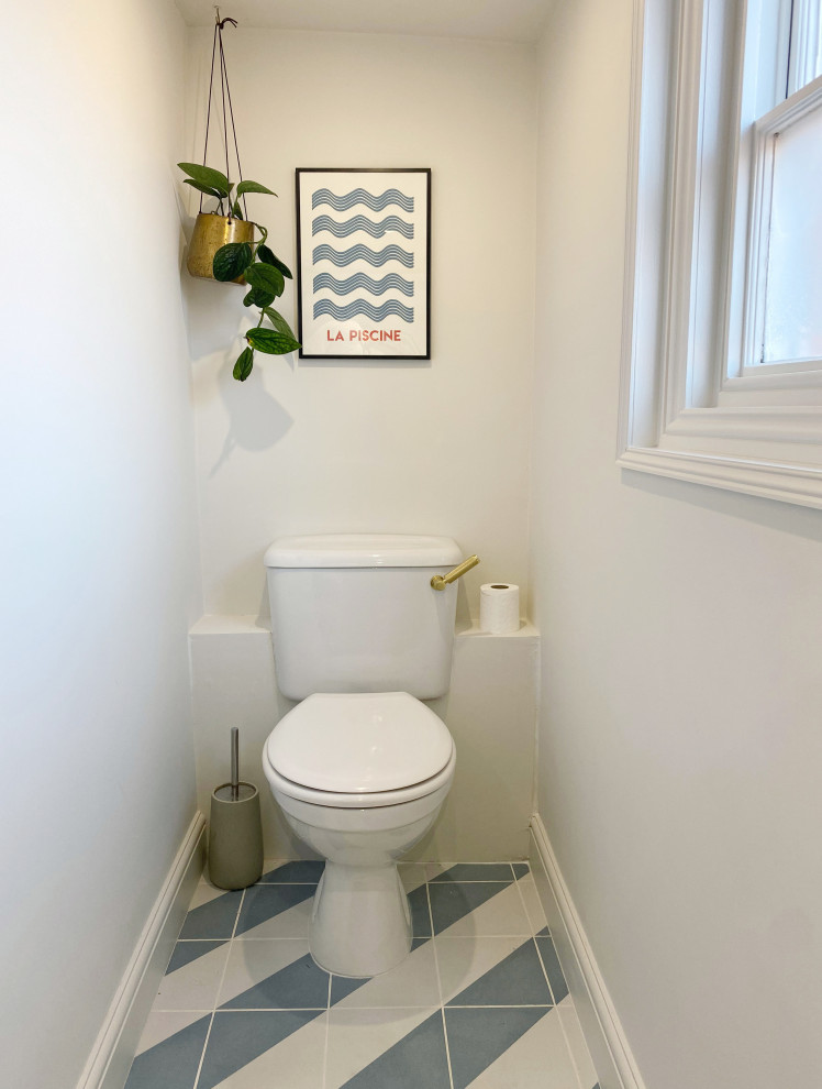 Foto på ett litet funkis svart toalett, med svarta skåp, en toalettstol med hel cisternkåpa, vit kakel, keramikplattor, vita väggar, klinkergolv i keramik, ett konsol handfat, träbänkskiva och blått golv