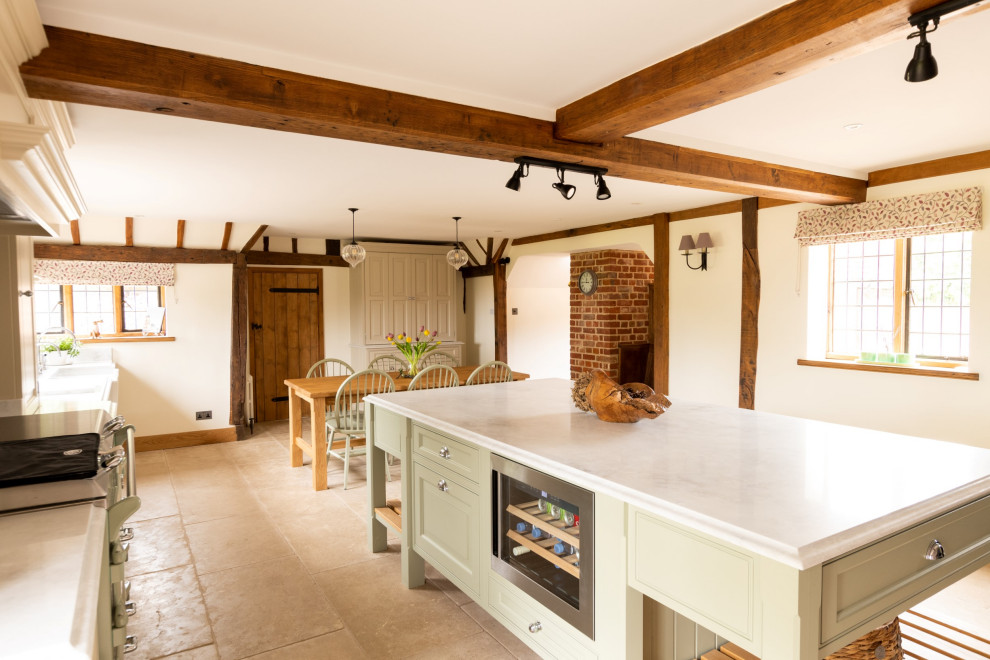 Expansive classic galley open plan kitchen in Essex with a double-bowl sink, raised-panel cabinets, green cabinets, quartz worktops, coloured appliances, porcelain flooring, an island, beige floors, white worktops, exposed beams and a feature wall.