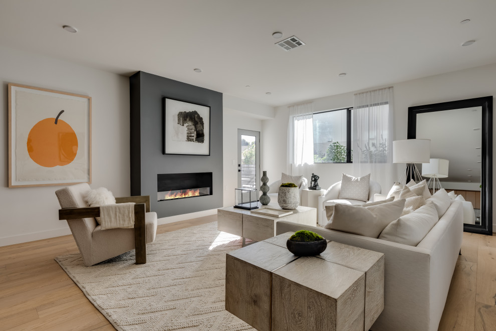 Photo of a contemporary formal open concept living room in Los Angeles with white walls, medium hardwood floors, a standard fireplace, no tv and brown floor.