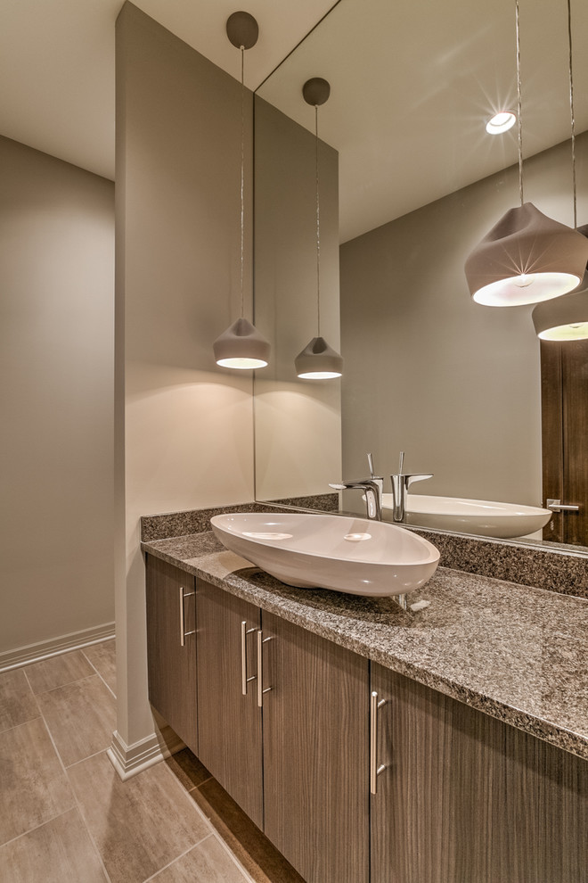 This is an example of a large contemporary powder room in Omaha with a vessel sink, flat-panel cabinets, dark wood cabinets, granite benchtops, a one-piece toilet, grey walls and porcelain floors.