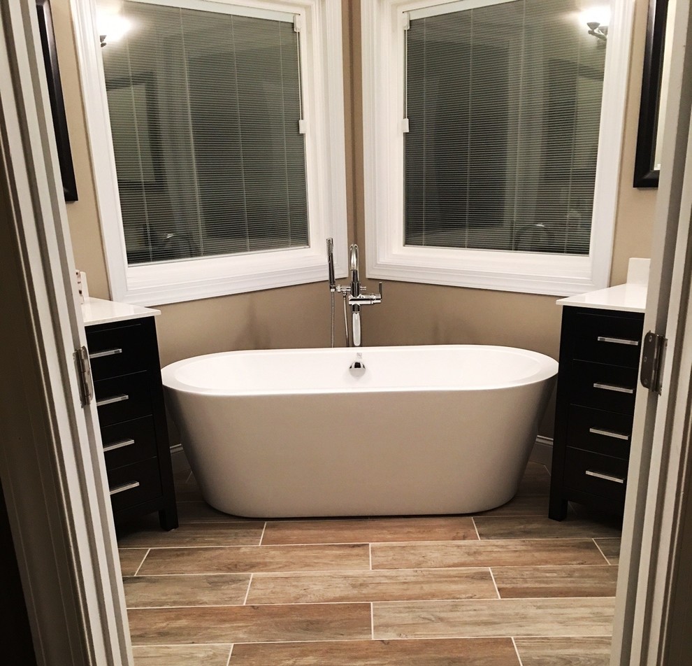 Inspiration for a mid-sized contemporary master bathroom in Raleigh with flat-panel cabinets, dark wood cabinets, a freestanding tub, beige walls, ceramic floors, an undermount sink and engineered quartz benchtops.
