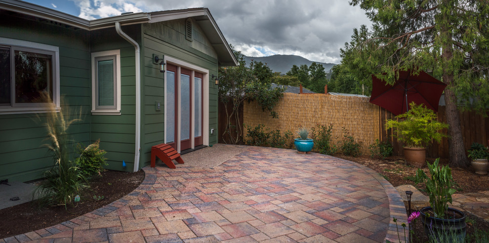 This is an example of an arts and crafts backyard patio in Other with concrete pavers.