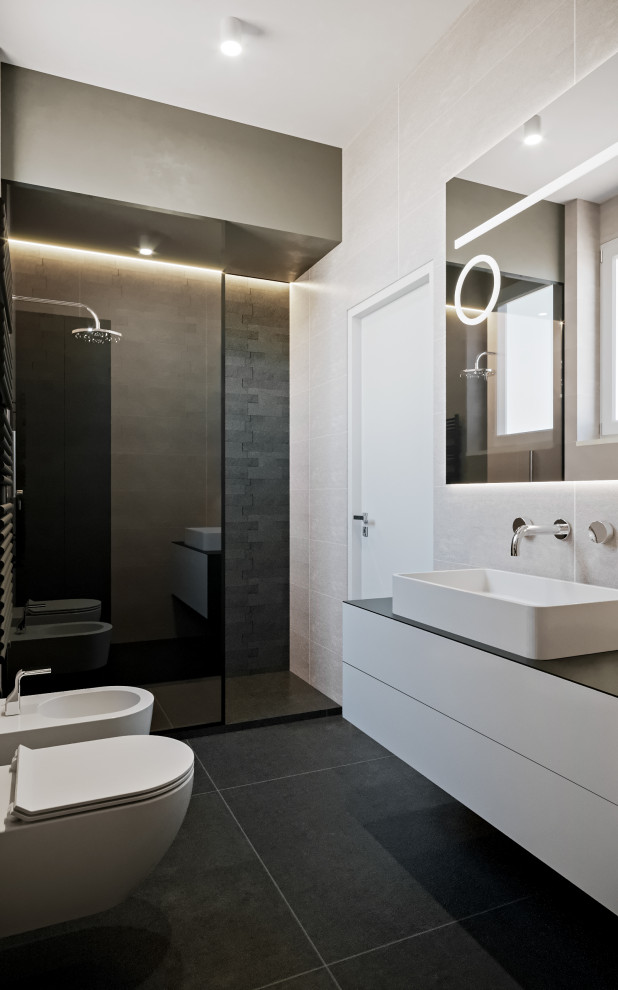 Modern inredning av ett mellanstort svart svart badrum med dusch, med släta luckor, grå skåp, en kantlös dusch, en toalettstol med separat cisternkåpa, grå kakel, porslinskakel, grå väggar, klinkergolv i porslin, ett fristående handfat, laminatbänkskiva, svart golv och med dusch som är öppen