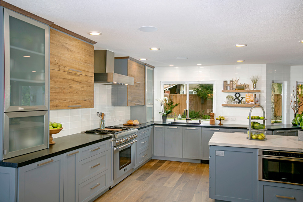 Inspiration for a large transitional u-shaped eat-in kitchen in San Diego with grey cabinets, white splashback, stainless steel appliances, medium hardwood floors, with island, an undermount sink, shaker cabinets, quartzite benchtops, subway tile splashback and brown floor.