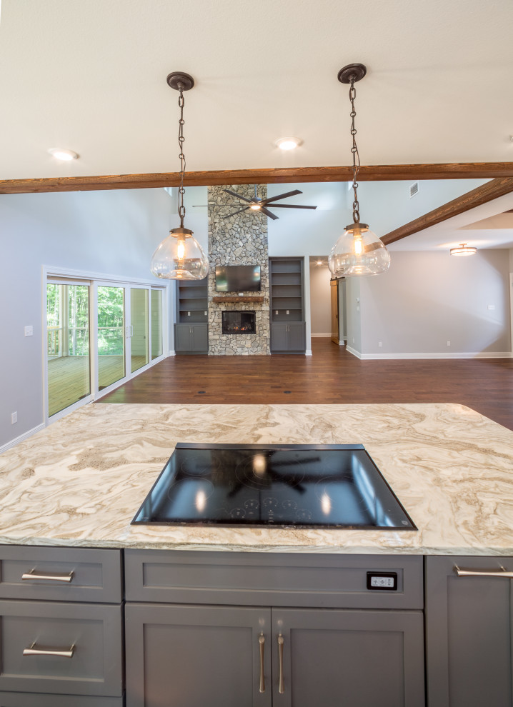 Mid-sized elegant galley medium tone wood floor and brown floor eat-in kitchen photo with a farmhouse sink, recessed-panel cabinets, white cabinets, quartzite countertops, white backsplash, glass tile backsplash, stainless steel appliances, an island and multicolored countertops