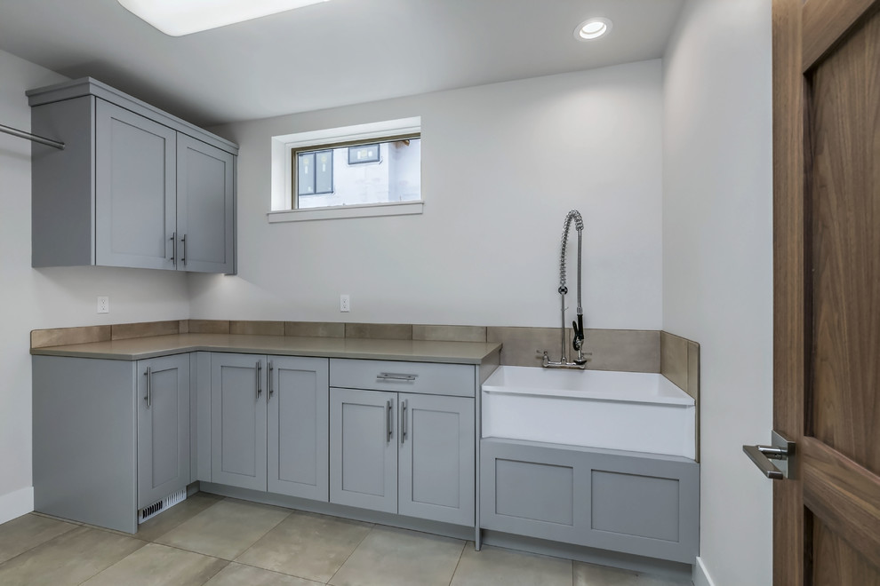 Example of a cottage porcelain tile and beige floor laundry room design in Other with an utility sink, shaker cabinets, gray cabinets, a side-by-side washer/dryer and beige countertops