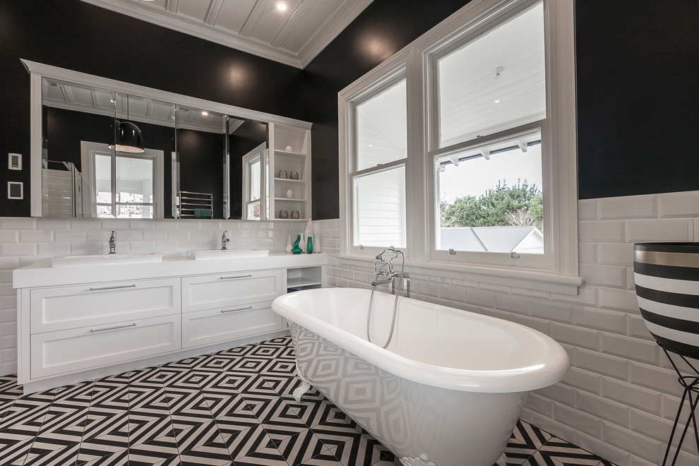 Inspiration for a large transitional master bathroom in Hamilton with recessed-panel cabinets, white cabinets, a claw-foot tub, a corner shower, a wall-mount toilet, white tile, subway tile, black walls, porcelain floors, a drop-in sink and solid surface benchtops.