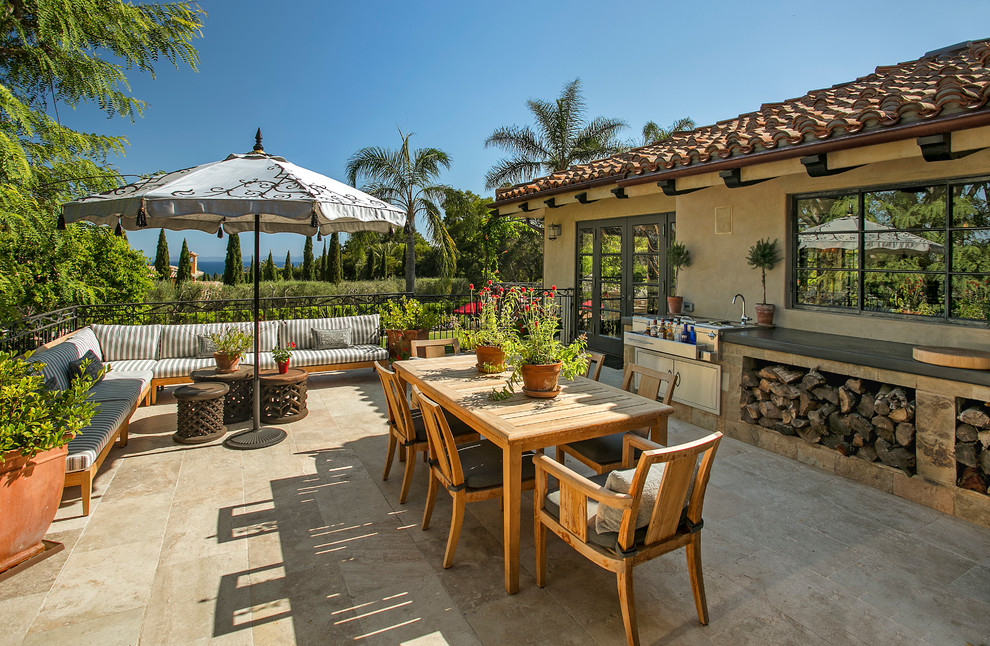 Large mediterranean patio in Santa Barbara with natural stone pavers and no cover.