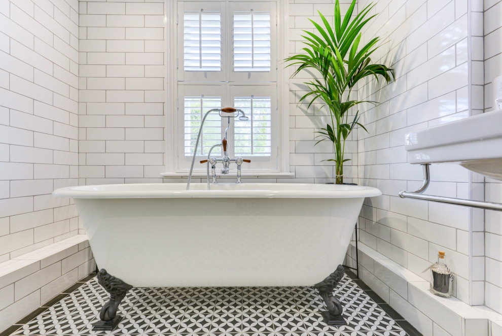 Design ideas for a medium sized victorian bathroom in Sussex with a freestanding bath, a corner shower, a two-piece toilet, white tiles, ceramic tiles, white walls, ceramic flooring, a pedestal sink, tiled worktops, multi-coloured floors, a sliding door, black worktops, feature lighting and a single sink.
