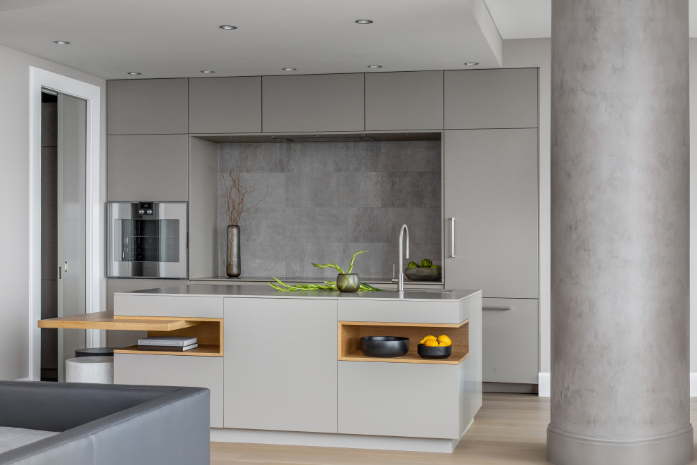 Design ideas for a contemporary eat-in kitchen in Seattle with an undermount sink, flat-panel cabinets, grey cabinets, quartz benchtops, grey splashback, panelled appliances, medium hardwood floors, with island, brown floor and grey benchtop.