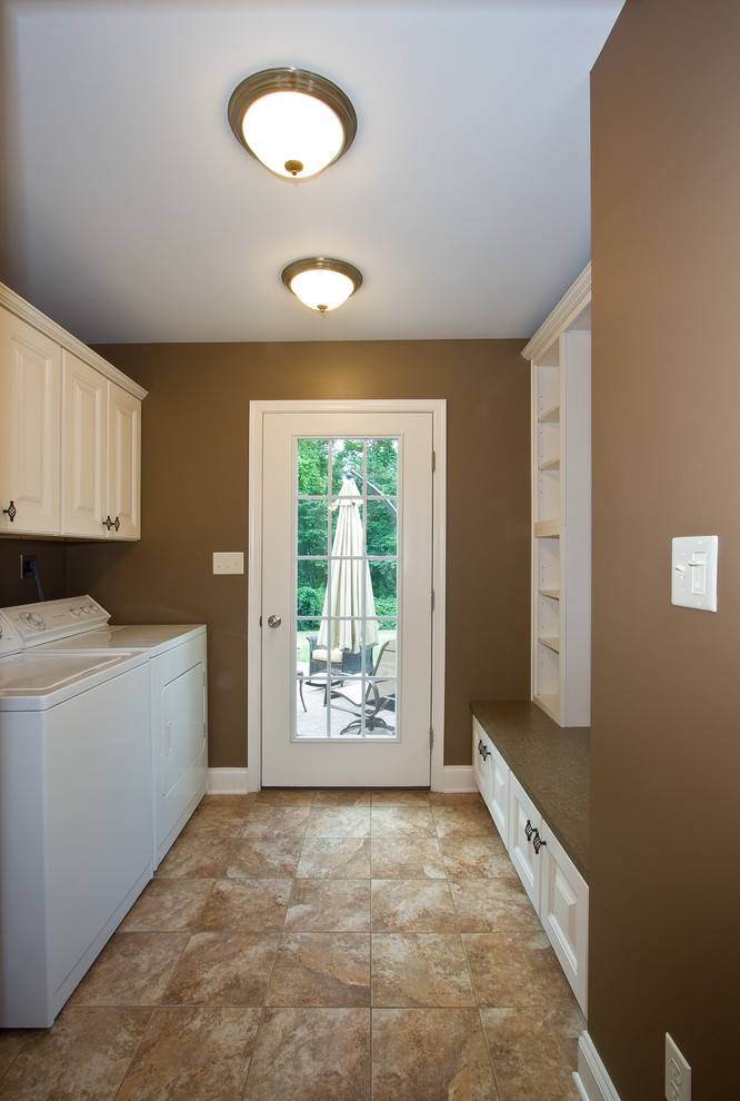 Design ideas for a mid-sized traditional galley utility room in Other with raised-panel cabinets, white cabinets, wood benchtops, brown walls, a side-by-side washer and dryer and beige floor.