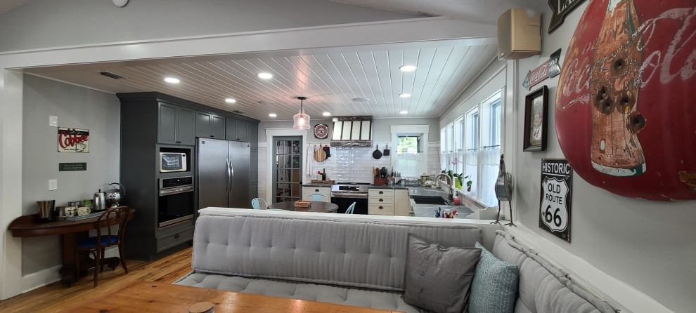 Example of a large u-shaped medium tone wood floor, brown floor and shiplap ceiling eat-in kitchen design with a farmhouse sink, shaker cabinets, gray cabinets, quartz countertops, gray backsplash, stainless steel appliances, a peninsula and black countertops