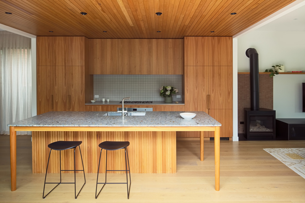 Exempel på ett stort modernt flerfärgad flerfärgat kök och matrum, med släta luckor, skåp i ljust trä, granitbänkskiva, beige stänkskydd, en köksö, stänkskydd i mosaik, rostfria vitvaror och ljust trägolv
