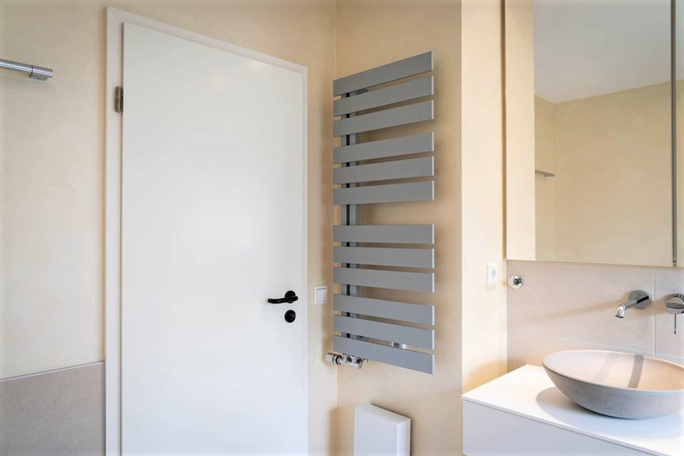 Duschbad With flächenbündigen Schrankfronten, beigen Schränken, Einbaubadewanne, Duschbadewanne, beigen Fliesen, Keramikfliesen, beiger Wandfarbe, Keramikboden, Wandwaschbecken, Beton-Waschbecken/Waschtisch, beigem Boden, Falttür-Duschabtrennung and weißer Waschtischplatte in Dusseldorf