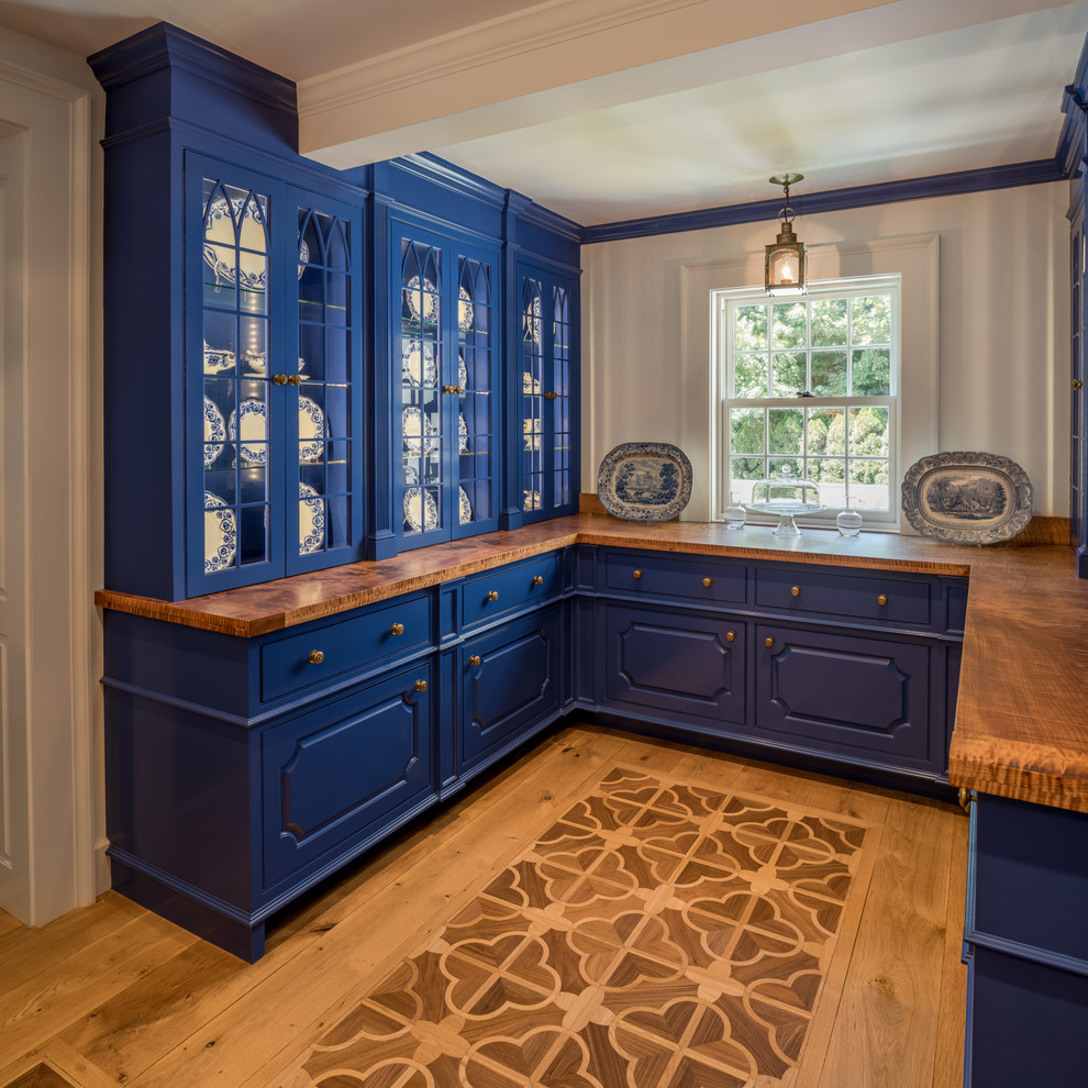 Inspiration for a mid-sized traditional u-shaped kitchen pantry in New York with raised-panel cabinets, blue cabinets, wood benchtops, light hardwood floors, beige floor and brown benchtop.