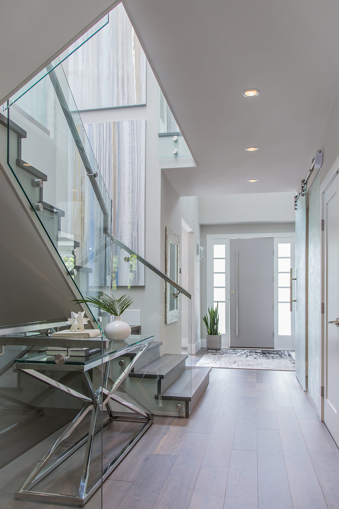 Photo of a mid-sized modern entry hall in Vancouver with beige walls, light hardwood floors, a single front door, a gray front door and brown floor.