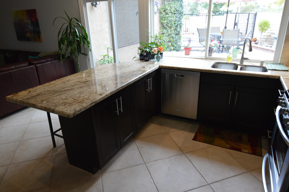Large transitional u-shaped separate kitchen in Los Angeles with a double-bowl sink, dark wood cabinets, granite benchtops, beige splashback, stainless steel appliances, shaker cabinets, stone tile splashback, ceramic floors and a peninsula.