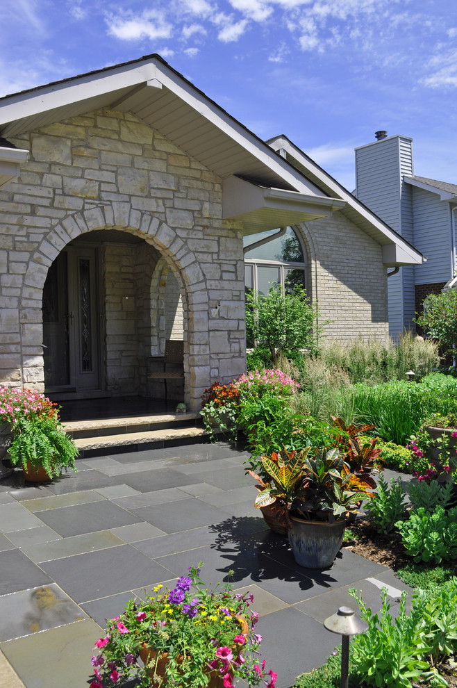 Design ideas for a mid-sized traditional front yard full sun garden in Chicago with natural stone pavers and a container garden.