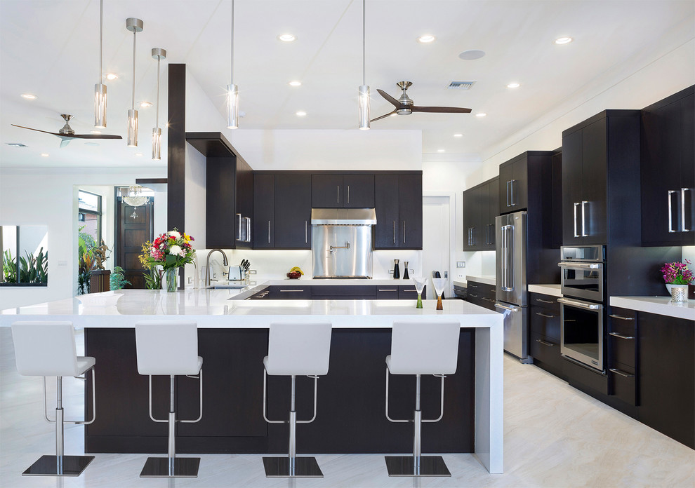 Photo of a large contemporary u-shaped kitchen in Miami with an undermount sink, black cabinets, marble benchtops, white splashback, stainless steel appliances, marble floors, a peninsula, flat-panel cabinets, white benchtop and beige floor.