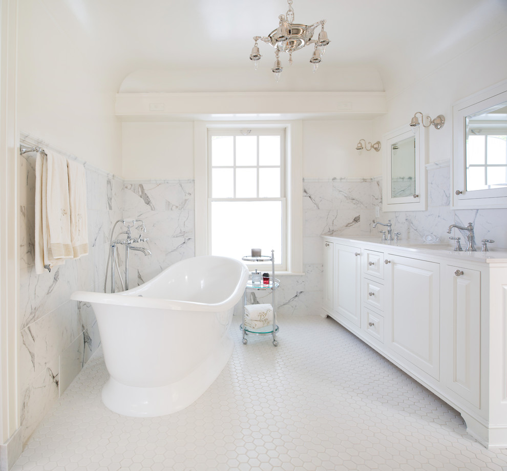 This is an example of a mid-sized traditional master bathroom in Kansas City with furniture-like cabinets, white cabinets, marble benchtops, a freestanding tub, an alcove shower, white tile, porcelain tile, white walls and porcelain floors.