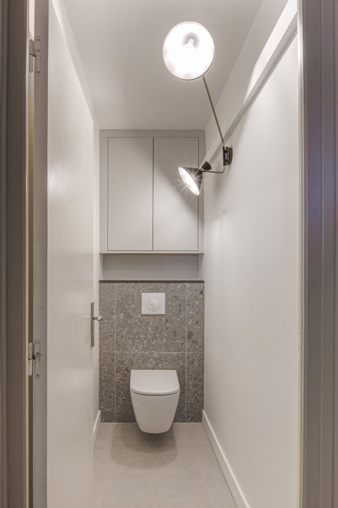 Modern inredning av ett stort vit vitt toalett, med en vägghängd toalettstol, grå kakel, vita väggar, klinkergolv i keramik, grått golv, släta luckor, skåp i mörkt trä, perrakottakakel och ett konsol handfat