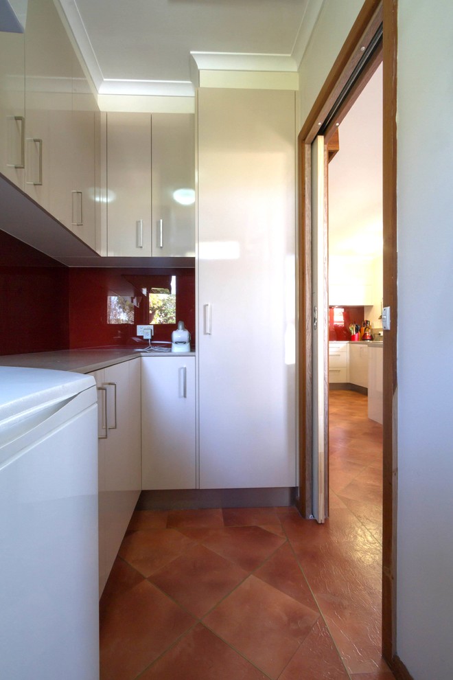 Mid-sized contemporary l-shaped dedicated laundry room in Melbourne with flat-panel cabinets and quartz benchtops.