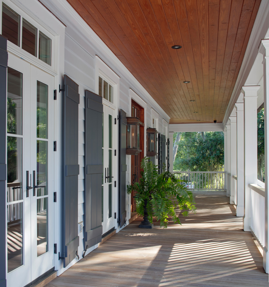 Inspiration for a large beach style front yard verandah in Other with with columns, decking and wood railing.