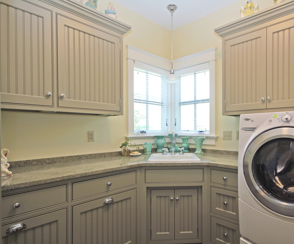 Photo of a mid-sized country l-shaped dedicated laundry room in Richmond with a drop-in sink, beaded inset cabinets, solid surface benchtops and a side-by-side washer and dryer.