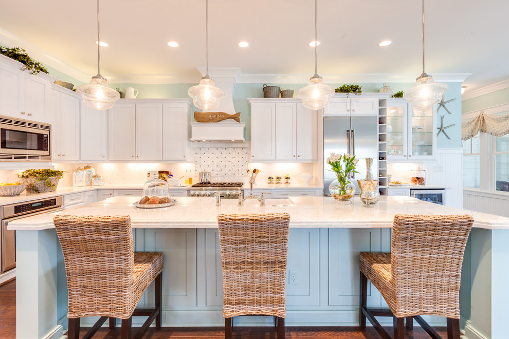 Inspiration for an expansive beach style l-shaped open plan kitchen in Other with a farmhouse sink, shaker cabinets, white cabinets, quartz benchtops, white splashback, stone tile splashback, stainless steel appliances, dark hardwood floors and with island.