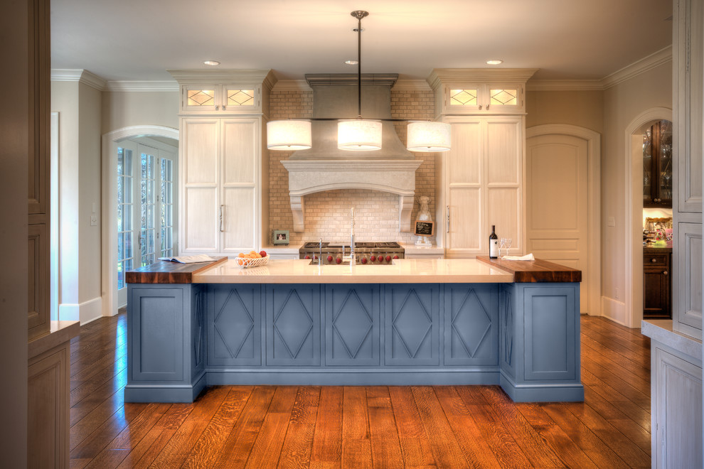 Open concept kitchen - huge transitional galley medium tone wood floor and brown floor open concept kitchen idea in Indianapolis with a farmhouse sink, flat-panel cabinets, white cabinets, wood countertops, white backsplash, brick backsplash, paneled appliances, an island and white countertops