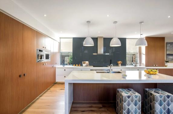 Inspiration for a large contemporary l-shaped kitchen pantry with an undermount sink, flat-panel cabinets, white cabinets, quartz benchtops, blue splashback, stainless steel appliances, light hardwood floors, with island and glass sheet splashback.