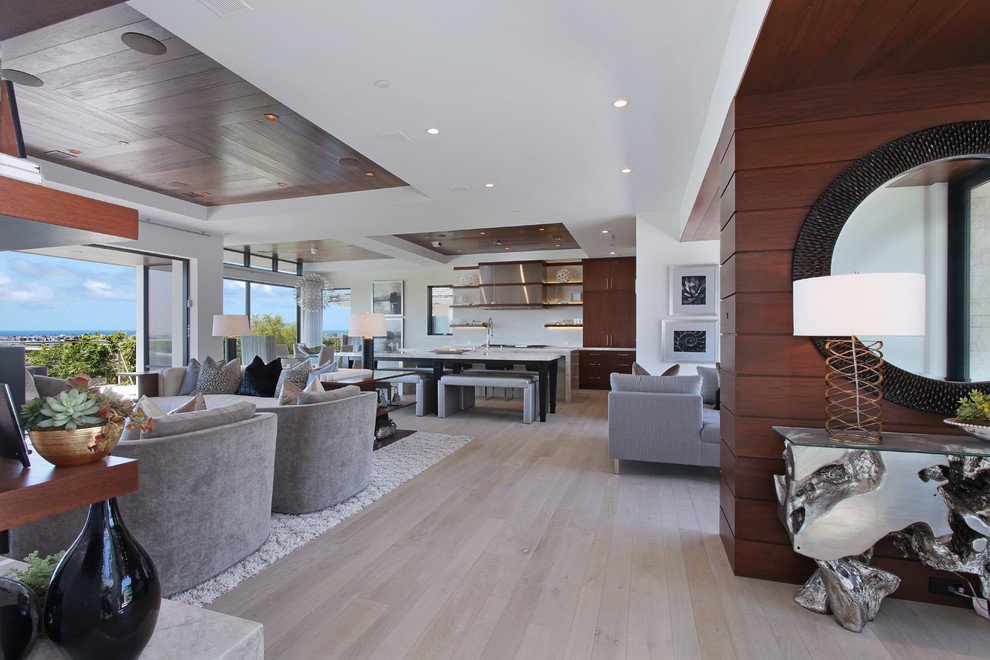 This is an example of a large contemporary open concept living room in Orange County with white walls, light hardwood floors and brown floor.