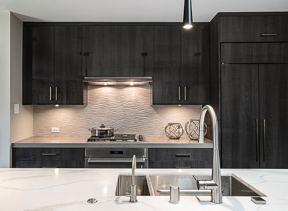 This is an example of a mid-sized contemporary galley open plan kitchen in Los Angeles with an undermount sink, flat-panel cabinets, quartz benchtops, beige splashback, porcelain splashback, panelled appliances, porcelain floors, with island, brown floor, white benchtop and black cabinets.