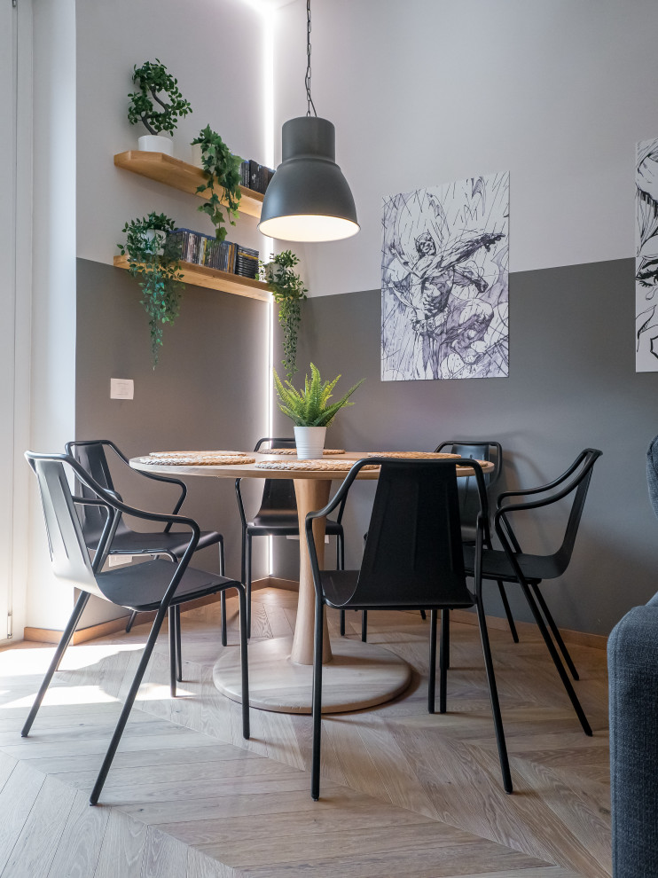 This is an example of a mid-sized industrial open plan dining in Milan with grey walls, light hardwood floors and recessed.