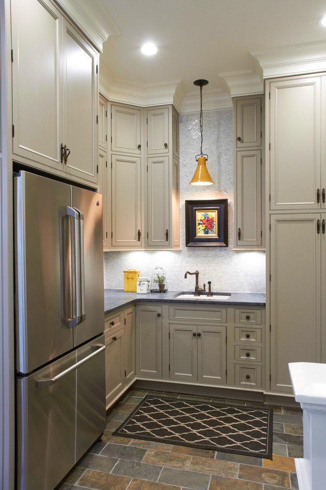 Example of a mid-sized transitional l-shaped slate floor and multicolored floor kitchen design with an undermount sink, recessed-panel cabinets, beige cabinets, quartz countertops, gray backsplash, ceramic backsplash, stainless steel appliances and an island