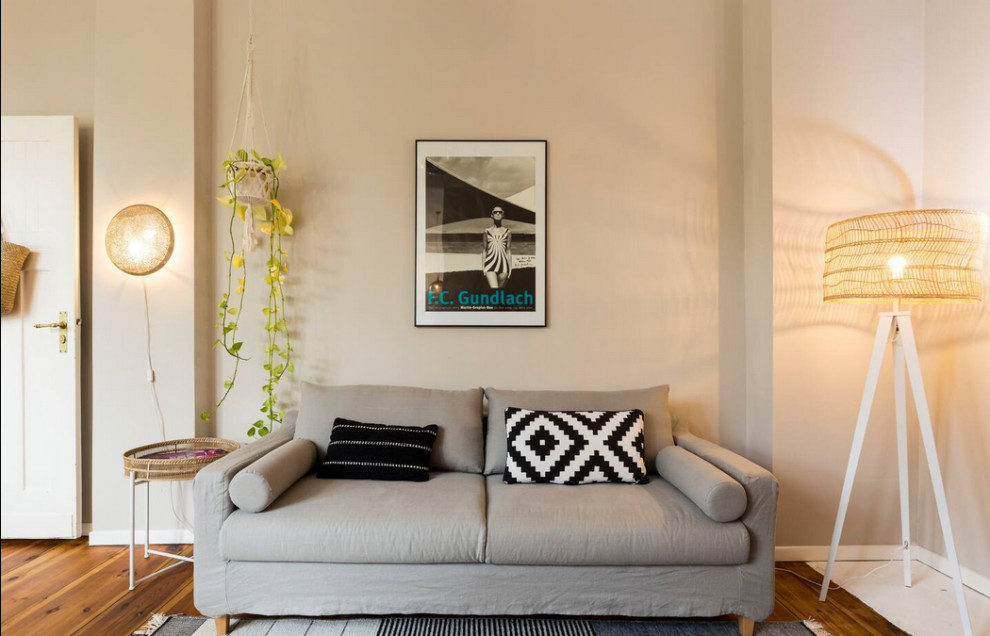 Exempel på ett mellanstort minimalistiskt allrum med öppen planlösning, med beige väggar, ljust trägolv och en fristående TV
