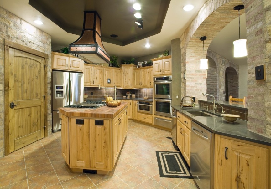 This is an example of a country kitchen in Denver with a single-bowl sink, raised-panel cabinets, distressed cabinets, granite benchtops, orange splashback, terra-cotta splashback, stainless steel appliances, terra-cotta floors and with island.