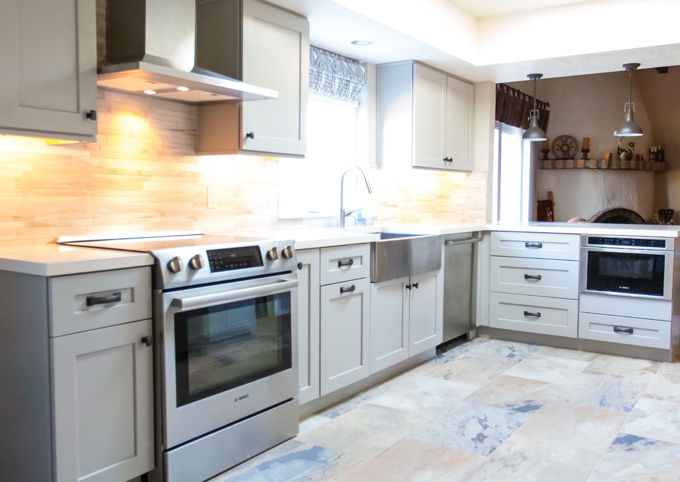 Example of a mid-sized transitional u-shaped porcelain tile kitchen design in Phoenix with a farmhouse sink, shaker cabinets, gray cabinets, quartz countertops, gray backsplash, porcelain backsplash, stainless steel appliances and a peninsula