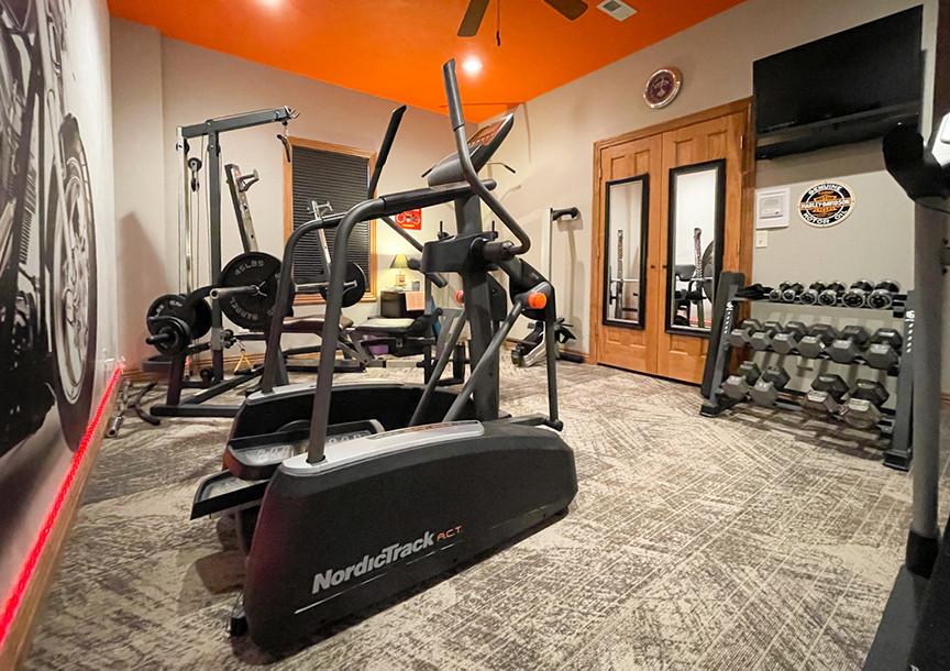 This is an example of a medium sized bohemian home weight room in Other with grey walls, carpet and grey floors.