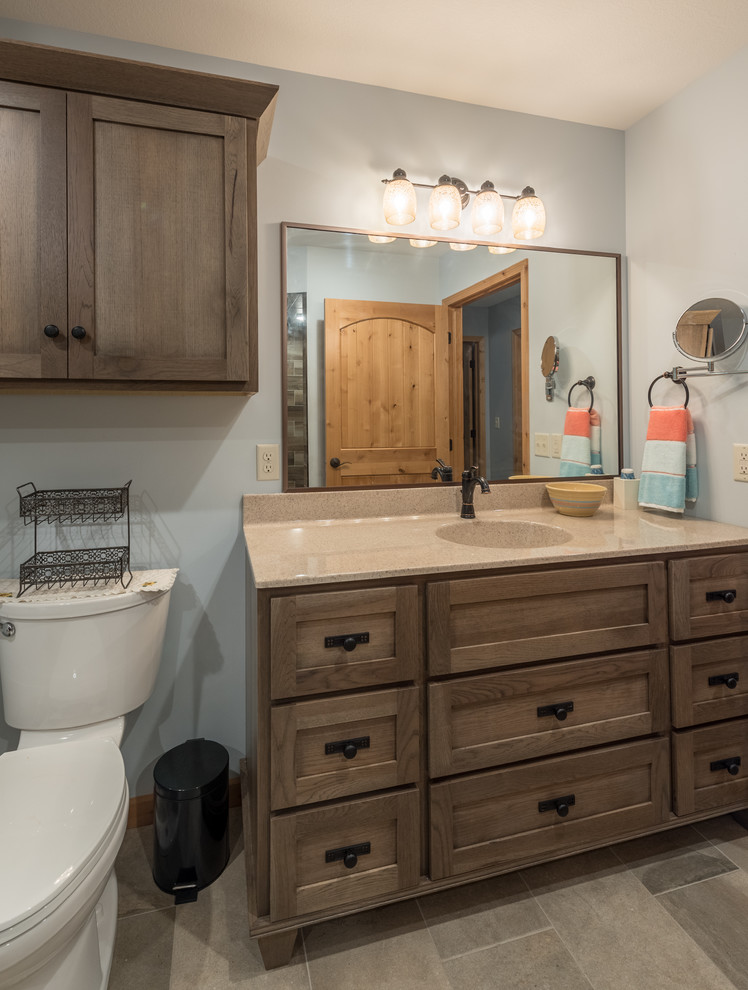 Example of a large transitional 3/4 beige tile, brown tile and porcelain tile porcelain tile and beige floor corner shower design in Minneapolis with shaker cabinets, brown cabinets, a two-piece toilet, blue walls, an integrated sink and beige countertops
