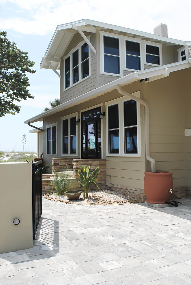 This is an example of a mid-sized traditional two-storey beige exterior in Tampa with vinyl siding and a gable roof.