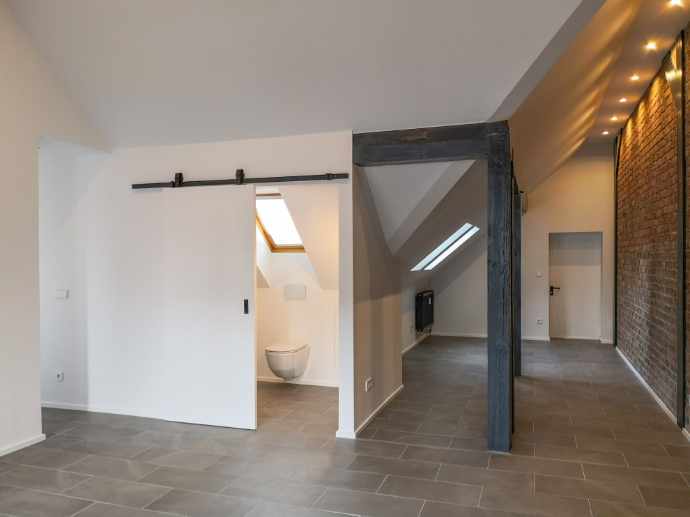 Geräumiges Modernes Schlafzimmer ohne Kamin mit weißer Wandfarbe, Keramikboden, grauem Boden und Ziegelwänden in Berlin