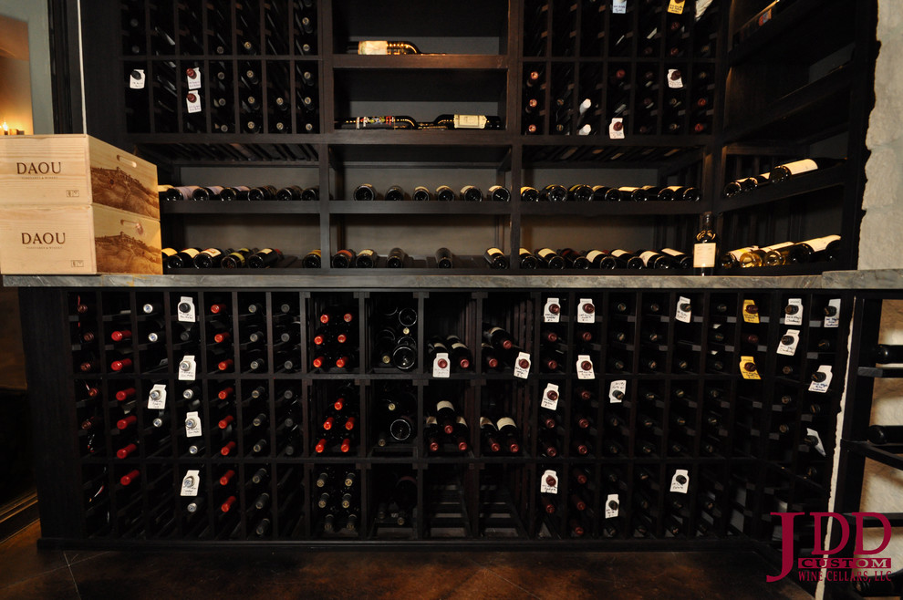 This is an example of a large mediterranean wine cellar in San Diego with concrete floors and display racks.