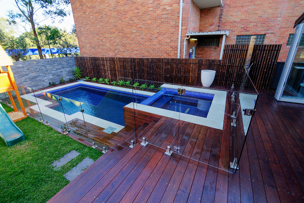 This is an example of a mid-sized contemporary backyard rectangular pool in Sydney with a hot tub and decking.